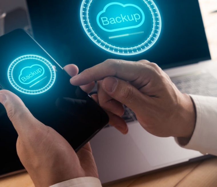 Businessman hand using smart phone and modern laptop computer with Cloud backup technology